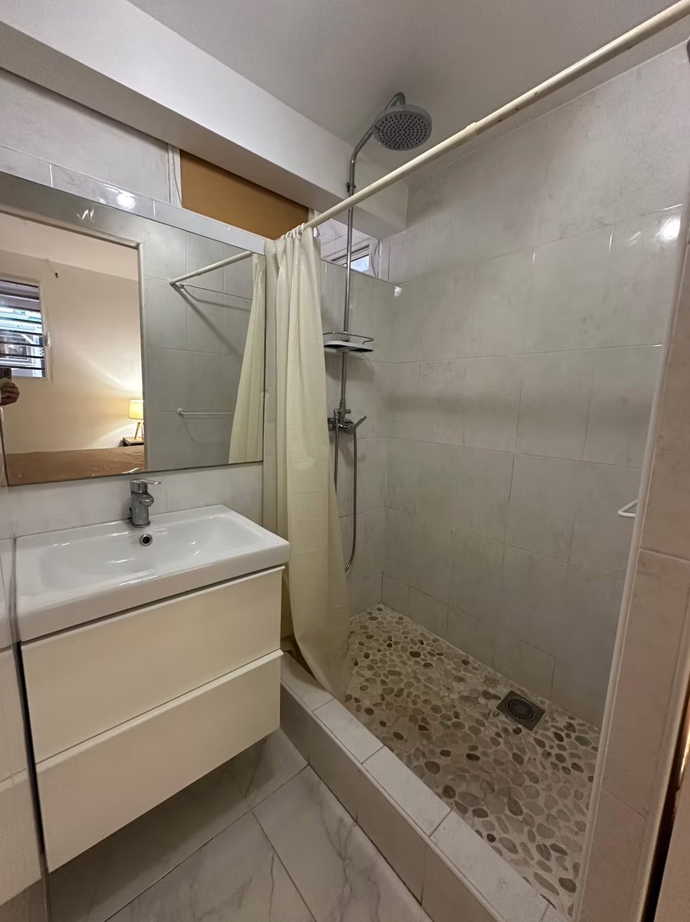 Salle de bain avec douche à l'italienne et vasque blanche.